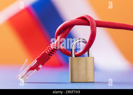 Geschlossenes Vorhängeschloss auf einem geknüpften Netzwerkkabel auf dem Hintergrund der russischen Flagge, das Konzept der Blockierung von Internetressourcen in Russland Stockfoto