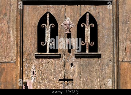Alte Holztür mit schwarzen Schmiededetails und altem Türklopfer in Hondarribia Stockfoto