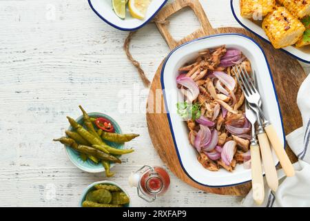 Gezapftes bbq-Hühnchen mit gebackenen Zwiebeln auf Servierplatte, bbq-Mais, Gurken, Chilischoten und Brötchen für Hot Dogs und Burger, Tomatensauce. Traditionell Stockfoto