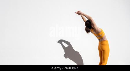 Weibliche Athletin, die sich an einer weißen Wand in einer Hinterbeugestellung befindet Stockfoto