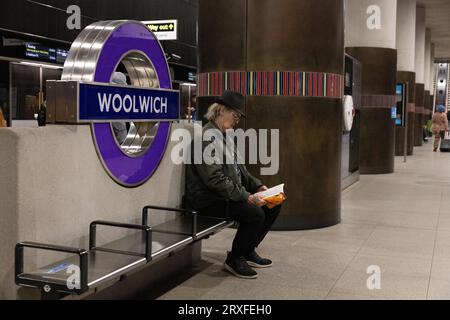 Mann, der sein Buch las, während er auf einen Zug an der Woolwich Elizabeth Line Station in East London, England, wartete Stockfoto