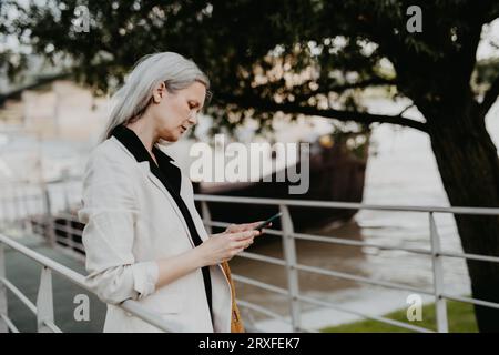 Porträt einer schönen Frau mit grauen Haaren in der Stadt, mit ihrem Smartphone. Stockfoto