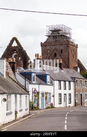 Das Dorf New Abbey mit Sweetheart Abbey, das sich über den kleinen Hütten in Dumfries, Schottland erhebt Stockfoto