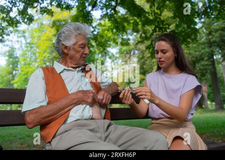 Die Krankenschwester injiziert Insulin in den Bauch eines diabetischen Seniorpatienten. Stockfoto