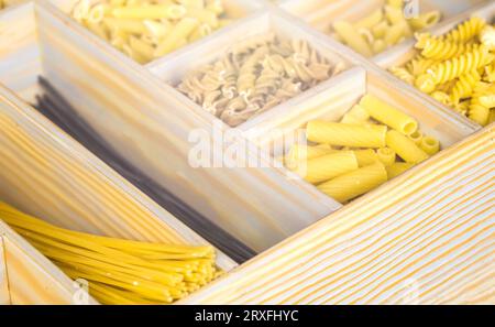 Verschiedene Pasta in Holzkiste. Italienische Nudelkollektion auf rustikalem Holztisch. Verschiedene Arten von Makkaroni, Nudeln trocken. Stockfoto