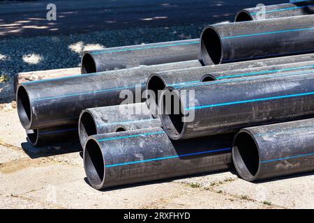 Schwarze Kunststoffleitungen. Ein Haufen von Polyethylenrohren für eine Wasserversorgung. Objekte für die Verlegung von Stadtkommunikation und Kanalisation. Die Konz Stockfoto