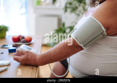 Übergewichtiger Mann, der seinen Blutdruck zu Hause misst. Stockfoto