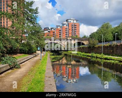 Großbritannien, West Yorkshire, Leeds, Brücke über Leeds und Liverpool Canal mit modernen Hochhausapartmentblocks im Hintergrund. Stockfoto