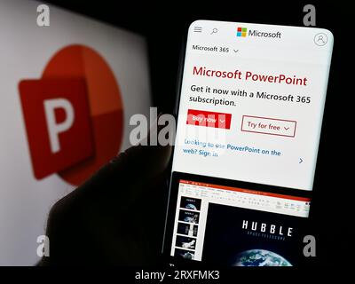 Person, die ein Smartphone mit einer Webseite mit Präsentationssoftware Microsoft PowerPoint auf dem Bildschirm vor dem Logo hält. Konzentrieren Sie sich auf die Mitte der Telefonanzeige. Stockfoto