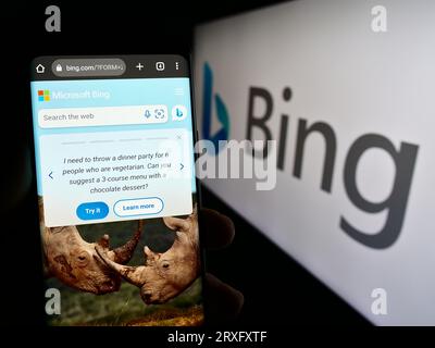 Person, die ein Mobiltelefon mit der Webseite der Web-Suchmaschine Microsoft Bing auf dem Bildschirm vor dem Logo hält. Konzentrieren Sie sich auf die Mitte der Telefonanzeige. Stockfoto