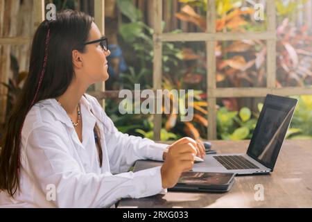 Junge Designerin mit digitalem Tablet und Laptop im Büro im Freien Stockfoto