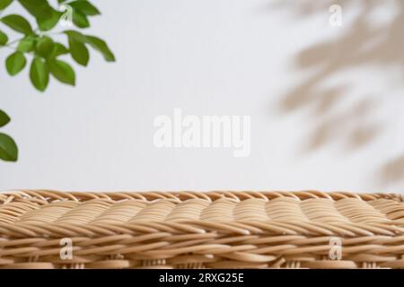 Hölzerne Rattan-Podium-Tischplatte verschwommene grüne Blattpflanze auf weißem Raum-Naturhintergrund. Schönheit kosmetische natürliche Produktanzeige. Stockfoto