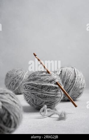 Häkelnadel aus Holz und Kugeln aus grauem Garn zum Häkeln und für Handarbeiten Stockfoto