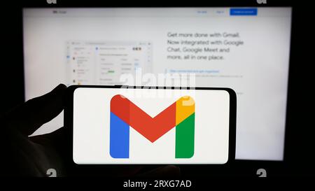 Person, die ein Smartphone mit dem Logo des E-Mail-Dienstes Google Gmail auf dem Bildschirm vor der Website hält. Konzentrieren Sie sich auf das Display des Telefons. Stockfoto