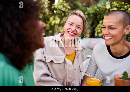 Ein glückliches Foto von drei reifen Freundinnen, die draußen was trinken. Stockfoto