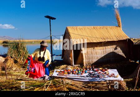 Uro-Frau mit Souvenirs auf der schwimmenden Insel „Chumi“, gebaut aus Totora-Schilf, Uro-Frau mit Souvenirs auf der schwimmenden Schilfinsel, Titicacasee Stockfoto