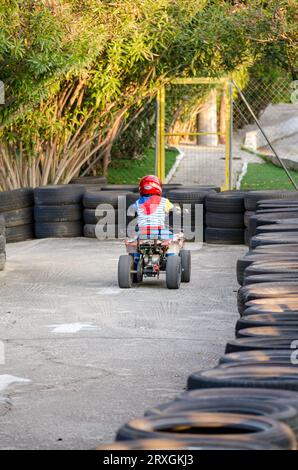 Kleiner Junge fährt ein Motorrad-ATV mit vier Rädern. Outdoor-Aktivität für Kinder auf einem Elektrorennen Quad Bike Maschine. Stockfoto