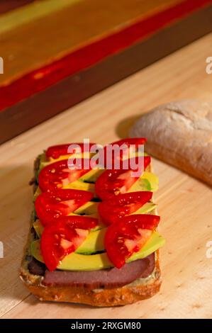 Bio-Tomaten-, Avocado- und Roastbeef-Sandwich auf handwerklichem Brot auf Holzuntergrund - Sándwich orgánico de Tomate, Aguacate y Roastbeef en Pan A Stockfoto