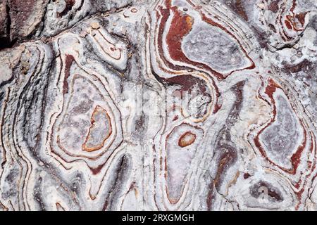 Ignimbrite vulkanische Felsformation mit Liesegang-Ringen. Die gelben Adern sind das Karosit-Mineral und rötlich sind Goethit. Dieses Foto wurde in Rodal aufgenommen Stockfoto