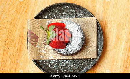 Genießen Sie ein Stück Zartbitterschokolade-Fondant und frische Erdbeeren. Stockfoto