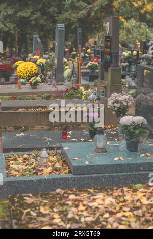 Brennende Kerzen in Laternen, dekorative Verzierungen und Chrysanthemenblüten auf dem Grab auf dem Friedhof Stockfoto