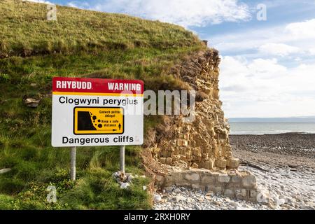 Zweisprachiges Warnschild „Dangerous Cliffs“ in der Nähe der Klippen am Llantwit Major Beach, Glamorgan, Wales. Stockfoto