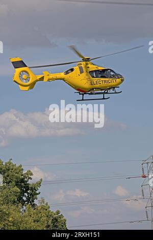 Hellgelber National Grid Elektrizitätshubschrauber im Flug, der Hochspannungsleitungen in der Nähe von Mickleton Chipping Campden UK überprüft Stockfoto