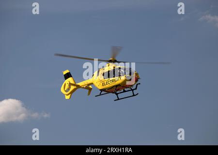 Hellgelber National Grid Elektrizitätshubschrauber im Flug, der Hochspannungsleitungen in der Nähe von Mickleton Chipping Campden UK überprüft Stockfoto