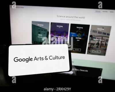 Person, die ein Mobiltelefon mit dem Logo der Online-Plattform Google Arts and Culture auf dem Bildschirm vor der geschäftlichen Webseite hält. Konzentrieren Sie sich auf das Display des Telefons. Stockfoto