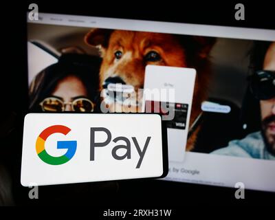 Person, die ein Mobiltelefon mit dem Logo des mobilen Zahlungsdienstes Google Pay auf dem Bildschirm vor der Firmenwebseite hält. Konzentrieren Sie sich auf das Display des Telefons. Stockfoto