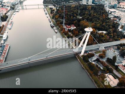 Luftaufnahme des UFO-Turms und der meisten SNP-Brücke im Herbst bei Sonnenuntergang - von der Drohne gemacht. Weitwinkelbild des berühmten UFO-Turms und der Donau in Brati Stockfoto