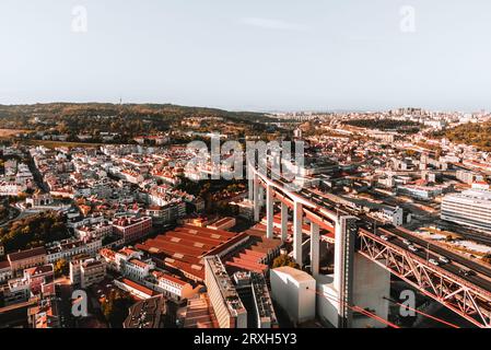 Horizontale Luftaufnahme von Straßen und Gebäuden Lissabons bei Sonnenuntergang. Die Brücke vom 25. april in Libson mit historischem Stadtzentrum und Dächern von abo Stockfoto