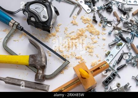 Ein Hintergrund mit Hardware, Handwerkzeugen und Holzspänen, isoliert in weiß. Stockfoto