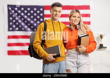 Studenten mit Rucksäcken und Büchern, die vor einer Flagge der USA stehen Stockfoto