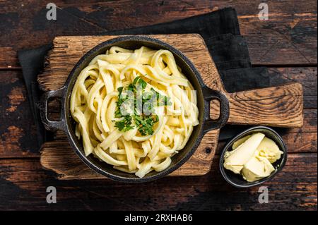 Deutsche Spaetzle-Eiernudeln mit Butter und Petersilie in einer Pfanne. Holzhintergrund. Draufsicht. Stockfoto