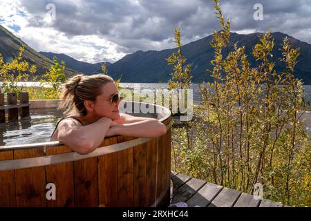 Frau, die in einem mit Holz befeuerten Whirlpool am Ufer eines Yukon Lake sitzt; Yukon, Kanada Stockfoto