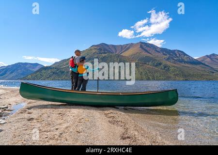 Paare, die einen ruhigen Moment mit ihrem Kanu am Ufer eines abgelegenen Yukon Sees an einem wunderschönen Sommertag verbringen; Yukon, Kanada Stockfoto