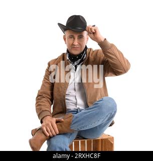 Reifer Cowboy, der auf weißem Hintergrund sitzt Stockfoto