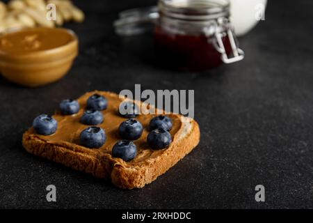 Toast mit Erdnussbutter und Heidelbeeren auf schwarzem Hintergrund Stockfoto