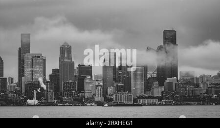 Seattle Skyline von West Seattle über Elliott Bay an einem verregneten Nachmittag mit einem Hauch von niedrigen Wolken und Nebel, die durch die hohen Gebäude treiben Stockfoto