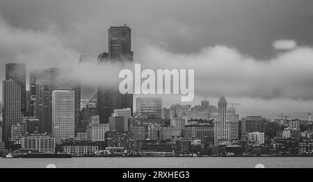 Seattle Skyline von West Seattle über Elliott Bay an einem verregneten Nachmittag mit einem Hauch von niedrigen Wolken und Nebel, die durch die hohen Gebäude treiben Stockfoto