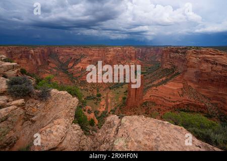 Landschaft des Canyon de Chelley, Arizona. Sturmwolken sammeln sich über dem Talboden, während die Felsformation, die als „Spinne“ bekannt ist, sich erhebt. Es ist... Stockfoto