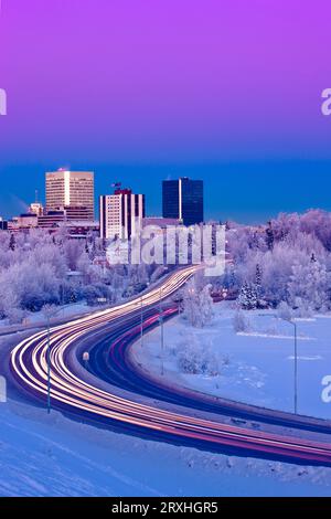 Alpenglow Über Der Anchorage Skyline Mit Den Lichtern Vom Verkehr Auf Dem Minnesota Blvd. Im Vordergrund Im Winter, Südzentrales Alaska Stockfoto