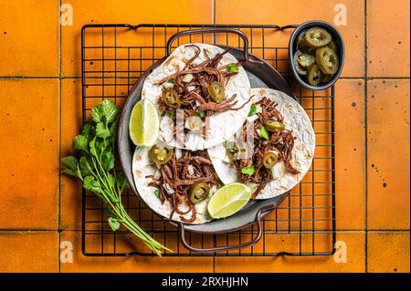 Scharfe Beef Barbacoa Tacos mit Cilantro und Zwiebeln. Orangefarbener Hintergrund. Draufsicht. Stockfoto