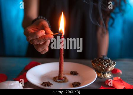 Eine rote Kerze anzünden, eine Hexe am Vorabend aller Heiligen ein Ritual, Halloween, spirituelle Überzeugungen, weiße Magie Stockfoto