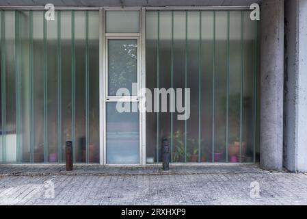 Glas- und Zementfassade im Erdgeschoss eines Wohngebäudes Stockfoto