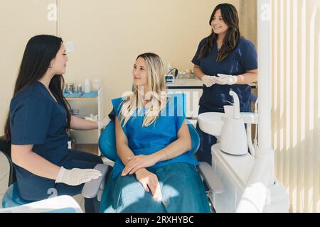Frau lächelt während ihrer Zahnarztbehandlung. Zahnärztinnen, die eine Patientin im Krankenhaus behandeln. Stockfoto