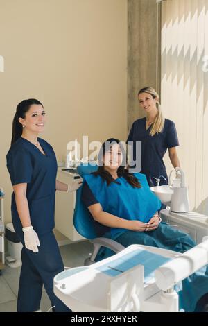 Porträt von drei Frauen, Zahnärztin, Assistentin und Patientin in einer Zahnarztpraxis, lächelnd und mit Blick auf die Kamera. Zahnärztliches Gesundheitskonzept. Stockfoto