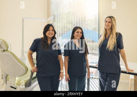 Das Konzept der Zahnheilkunde. Zahnärztliche Leistungen. Ein Team von Fachleuten in einer Zahnklinik. Drei schöne Zahnärztinnen lächeln und sehen sich die Kamera im Zahnarzt an Stockfoto