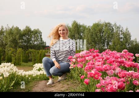 Glückliche Frau im schönen Tulpenfeld draußen Stockfoto